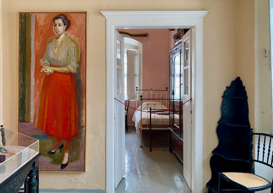 A large oil painting of a woman, hung next to an open bedroom doorway