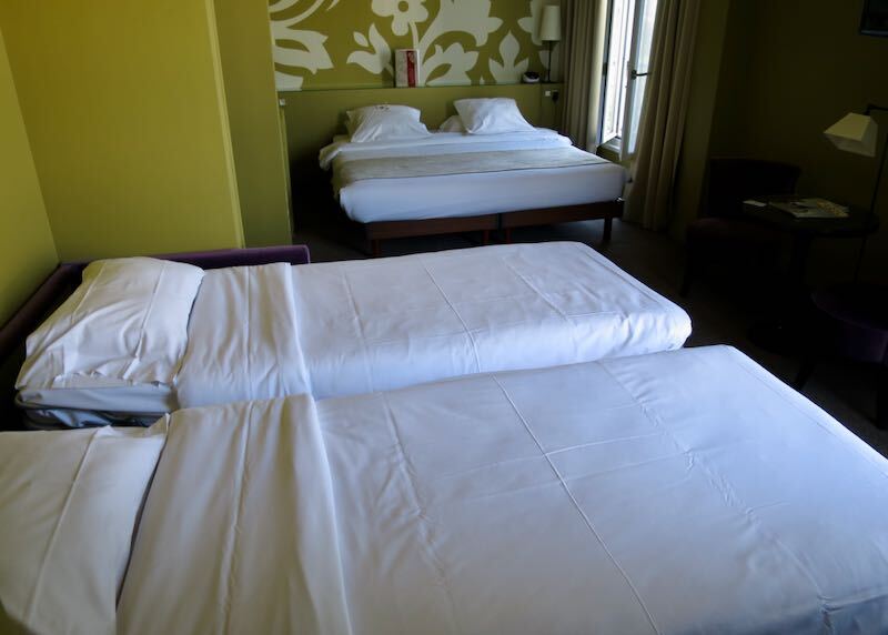 A hotel room with one double bed and two single beds at Gardette Park Hotel in Paris.