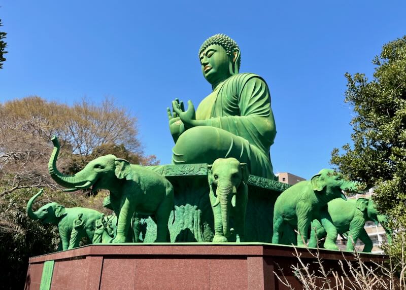 Sculptures of green elephants surround a green Buddha.
