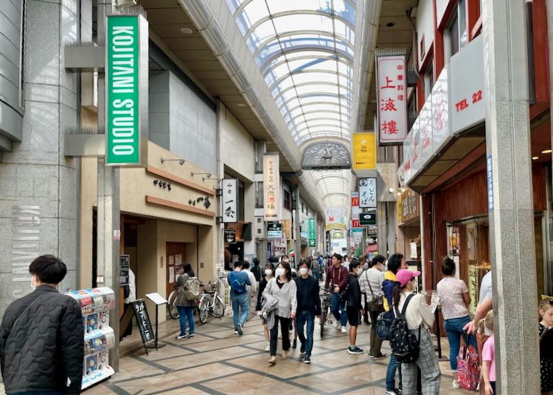 People walk around the covered Higashimuki Shopping Street.