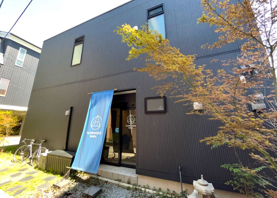 A small dark building with a blue sign that reads "Slowhouse Nara."