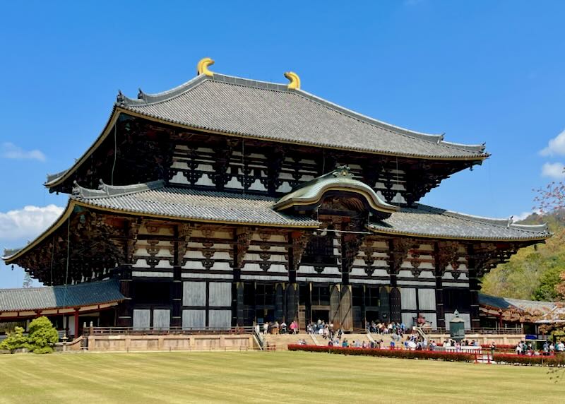A large temple with wood ornamentation and gold horns on the roof.