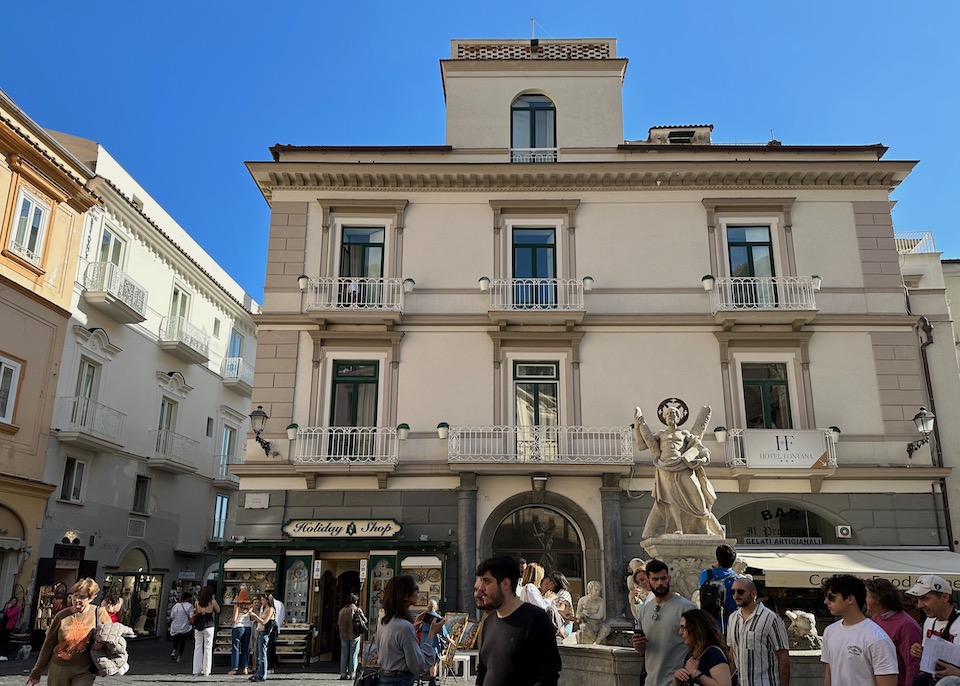 Exterior of Hotel Fontana in the main square of Amalfi with Saint Andrew's Fountain and pedestrians