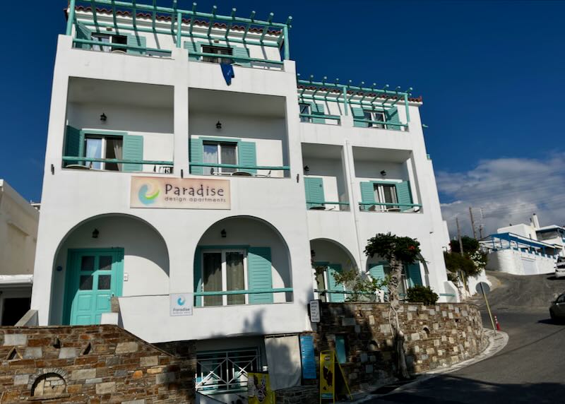 White hotel with turquoise shutters and balconies against a blue sky