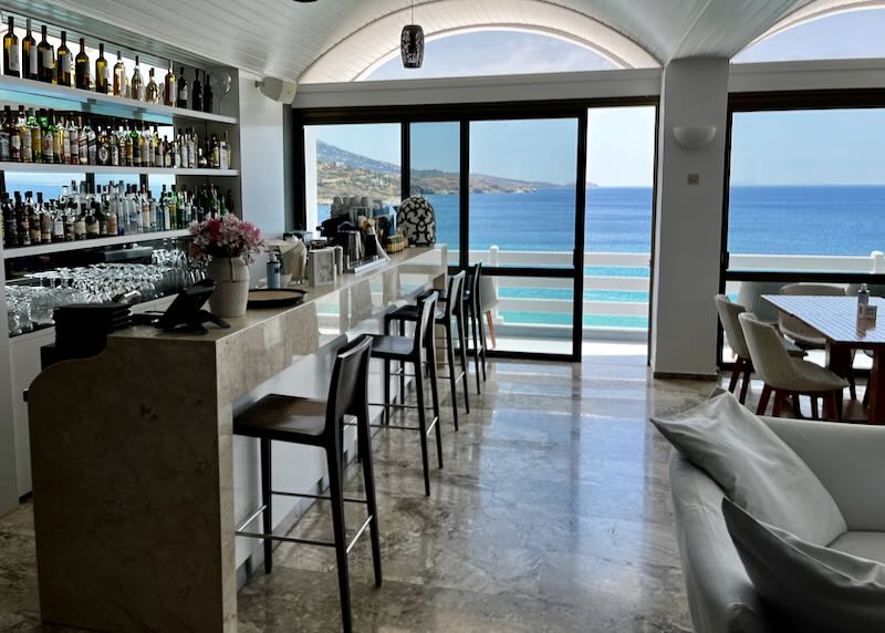 Hotel bar with a sliding glass door that opens to a sea-view terrace