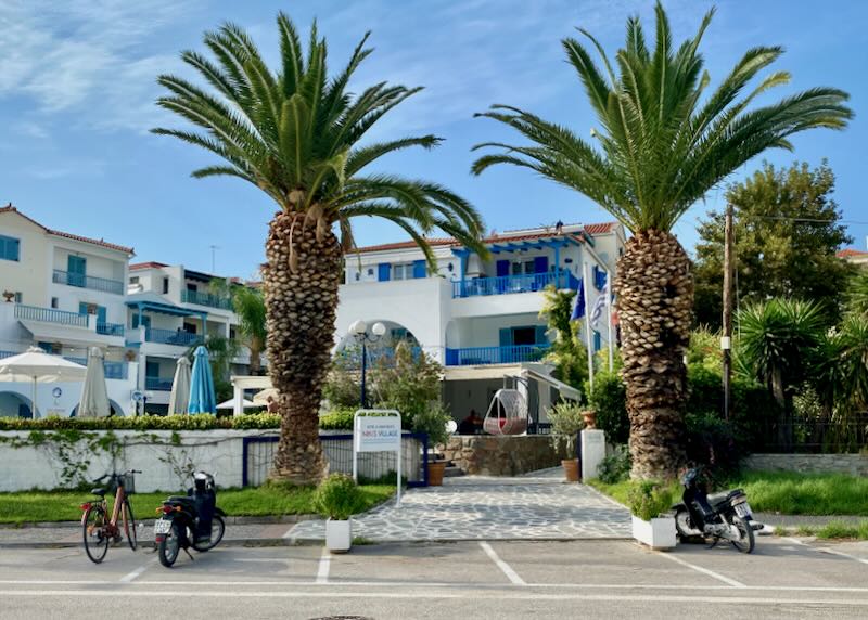 White villa-style hotel with palm trees and bikes in front