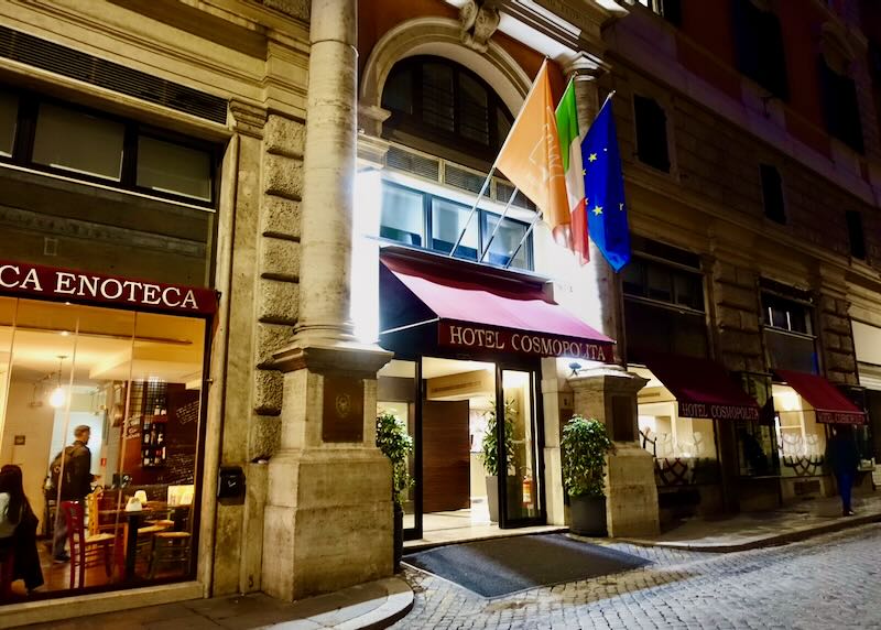 Hotel doorway at night, lit up, and with flags flying.