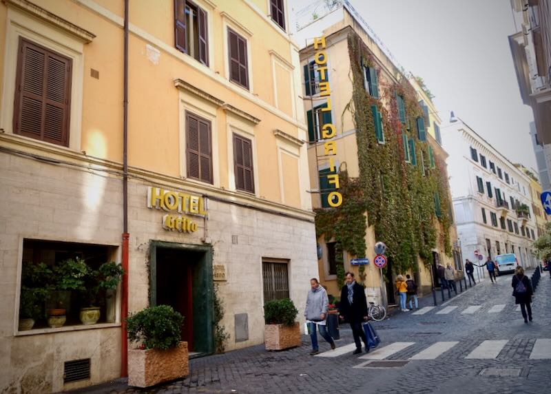 View of a small hotel on a quiet street in Rome, with pedestrians walking by.