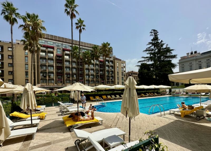 Outdoor hotel swimming pool surrounded by sun loungers and palm trees