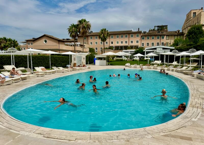 Families splash and play in an outdoor hotel swimming pool.