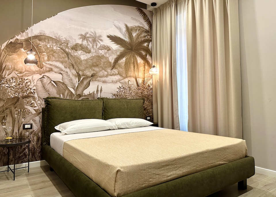 Inside a deluxe double room in earth tones with a jungle fauna mural at Les Lumieres in Centro Nuovo in Salerno