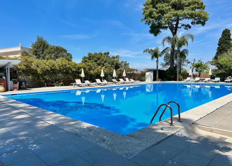 Pool and sunbeds with trees at Hotel La Cocumella in Sorrento