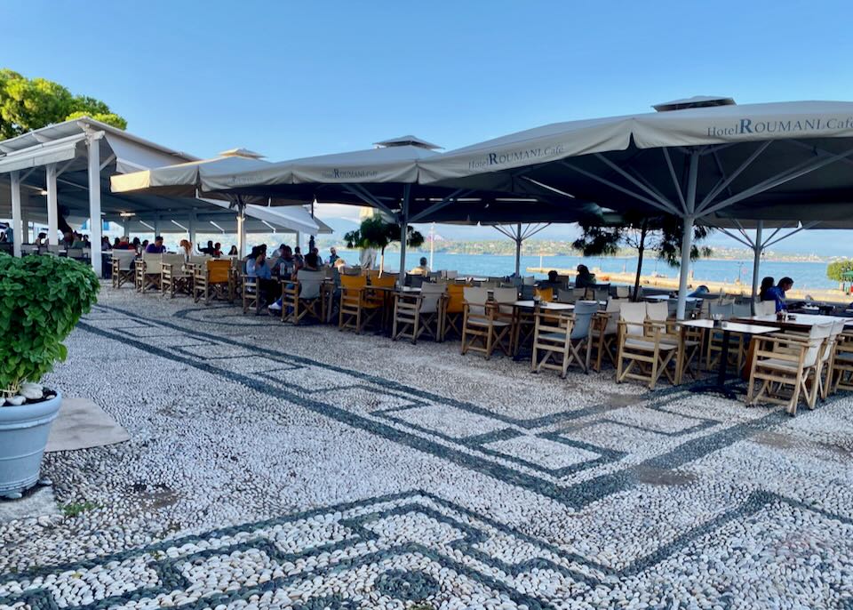 Shaded café tables overlooking a small seaport