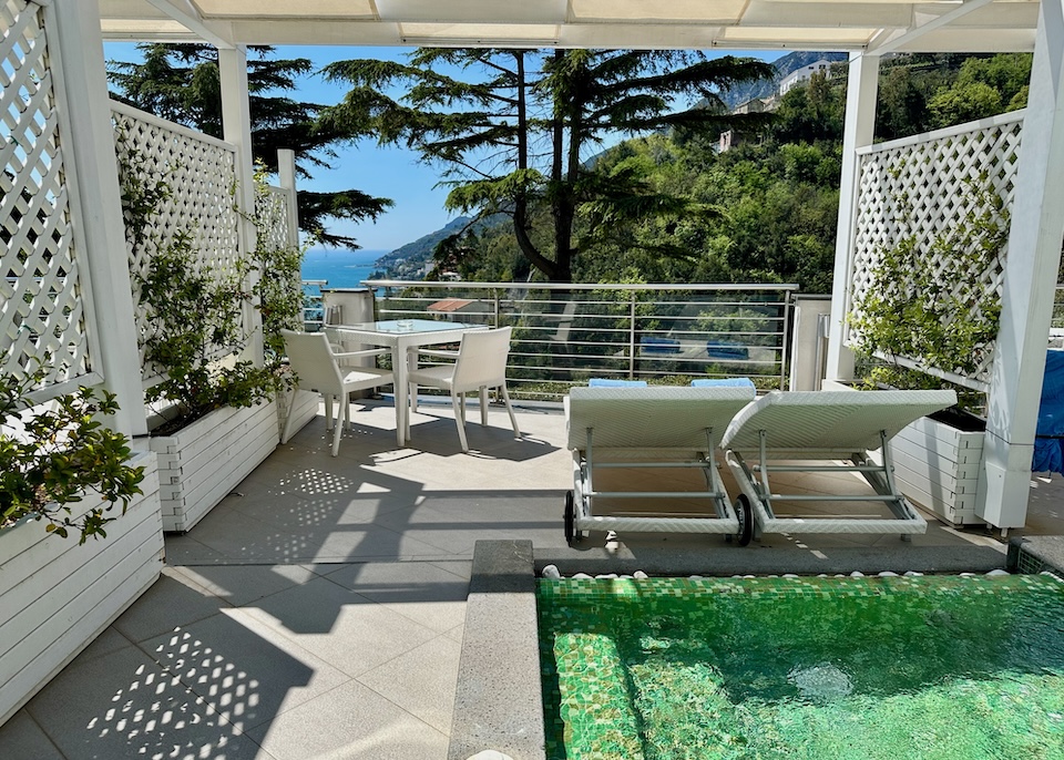 Sunny terrace with a mosaic tile jacuzzi, two sunbeds, and a small dining table in the Junior Suite at Relais Paradiso in Vietri sul Mare on the Amalfi Coast