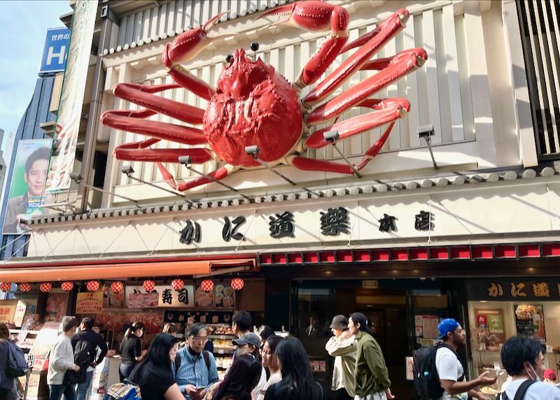 A giant plastic crab sits on the wall above the entrance to a restaurant.