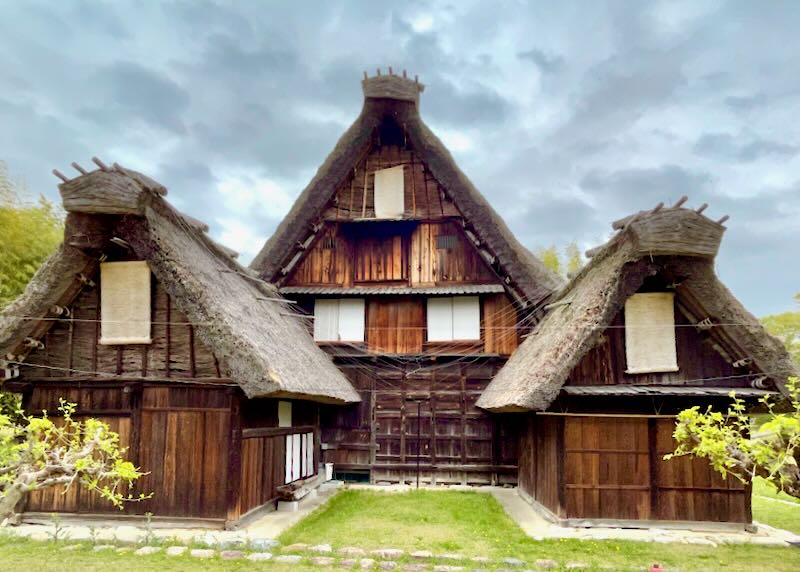A house made of burned wood and a steep thatched roof.