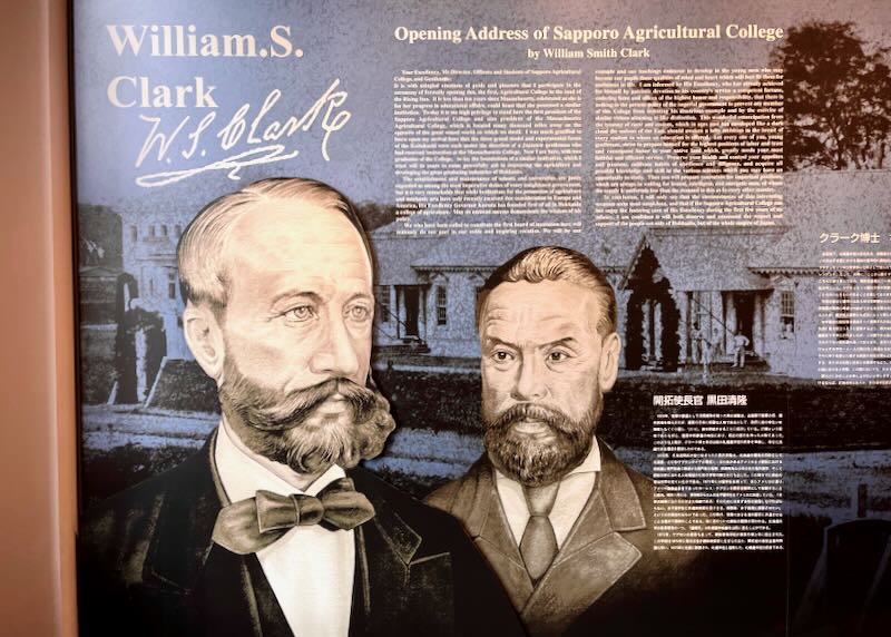 Illustrations of two men and their history is displayed on a museum wall.