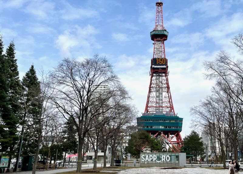 A red metal tower with green decks and a large digital clock that reads 1:50.