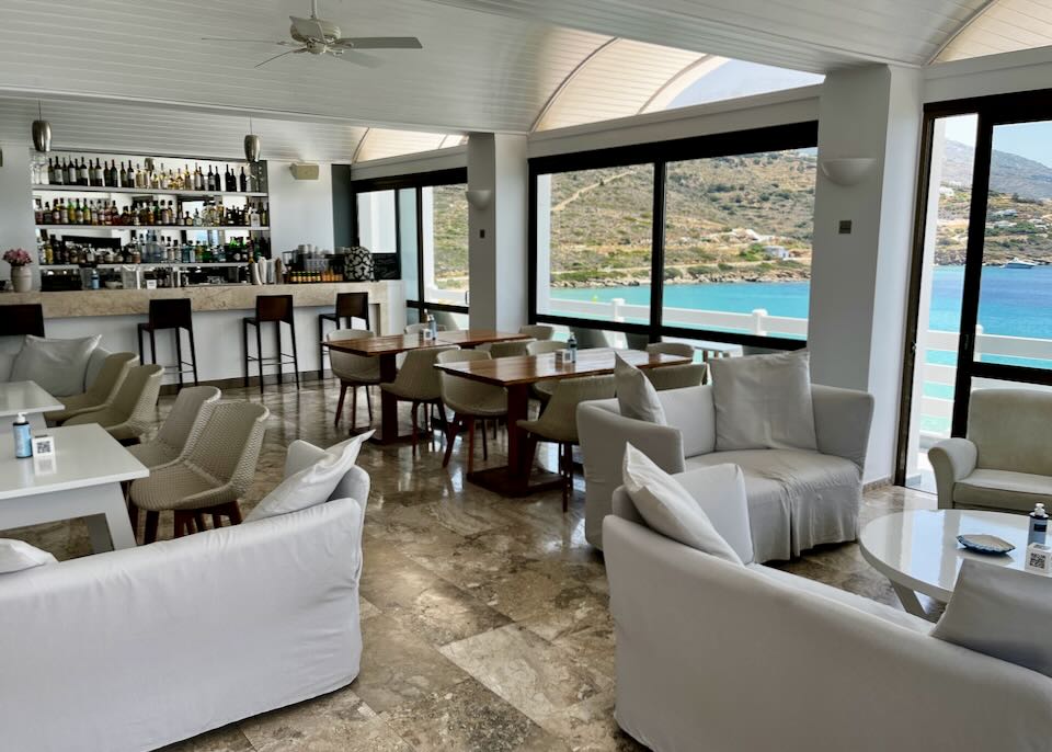 Dining room with white furniture, a bar, and views of a blue sandy bay