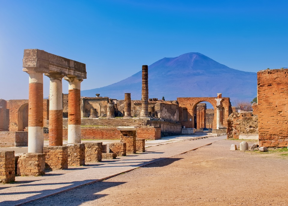Ancient columnds and walls in the ancient city of Pompeii with Mount Vesuvius in the background