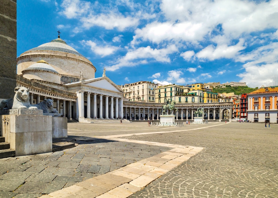 In the Piazza del Plebiscito with the dome of the Basilica of San Francesco da Paola plus numerous statues and colorful buildings in Naples, Italy