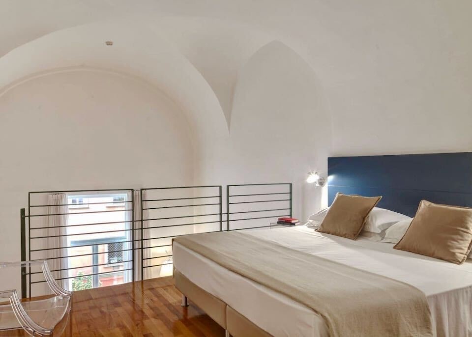 The top floor of a loft room with a bed and clear chair at Piazza Bellini Hotel in Naples, Italy
