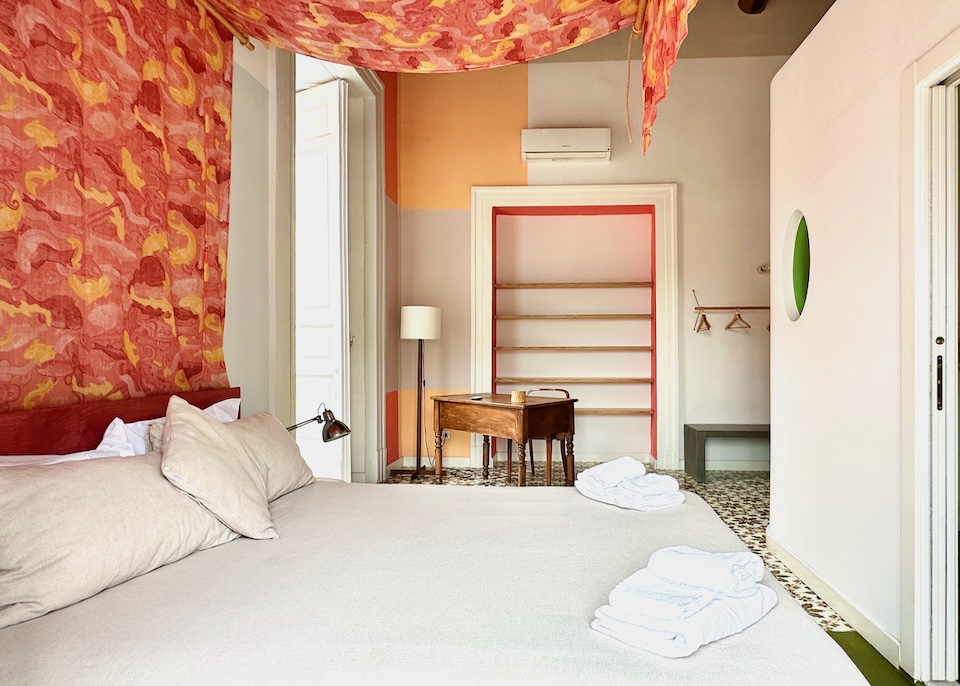 Bed with a red and orange canopy in a room with a maiolica tile floor at Super Otium Hotel in Naples, Italy