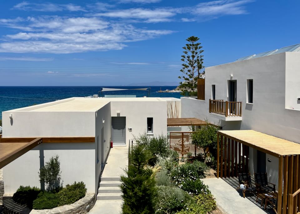 White boxy hotel with pine trees and the sea in the background