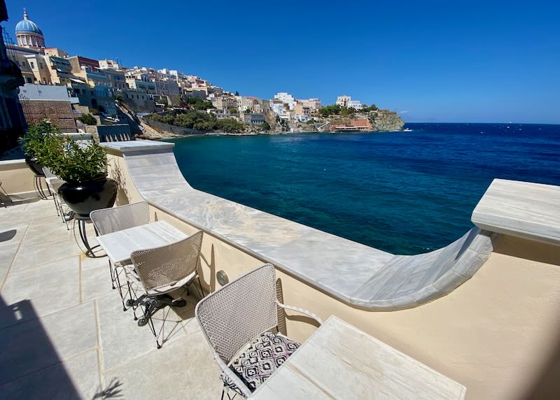 View from a marble terrace over the blue sea and a neoclassical Greek seaside village
