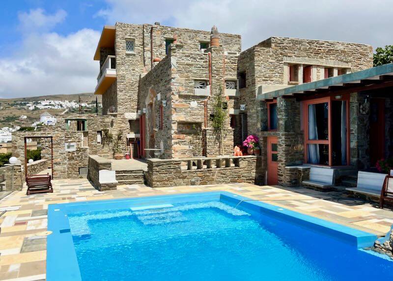 Boxy stone hotel surrounding a swimming pool terrace