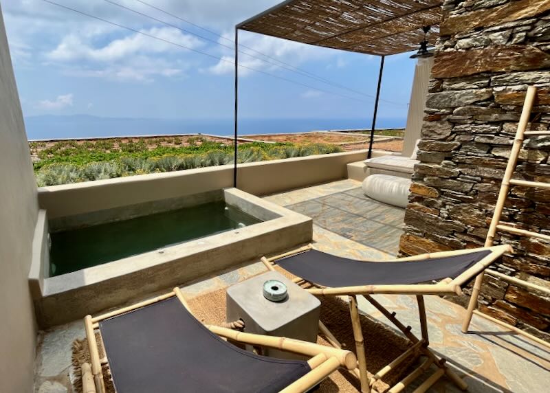 Two wood-and-fabric sun loungers overlooking a private plunge pool to the sea