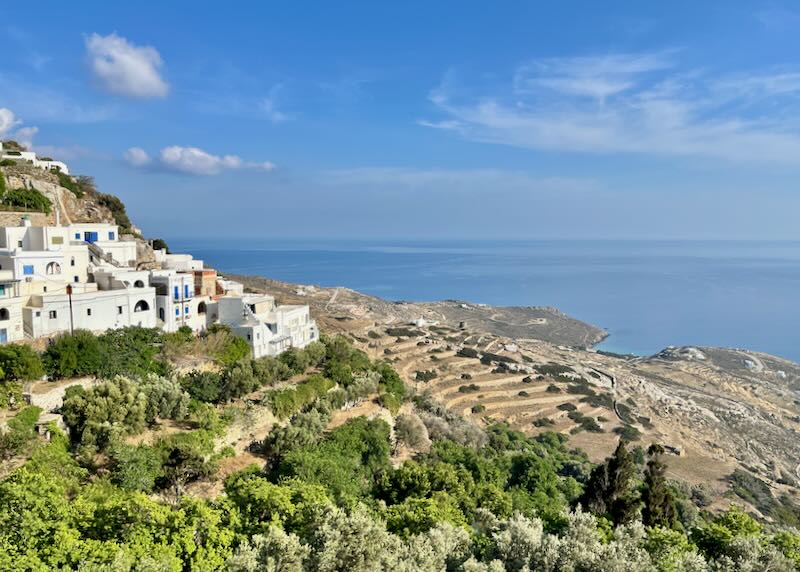 Village of white boxy buildings perched on a hillside leading down to the sea