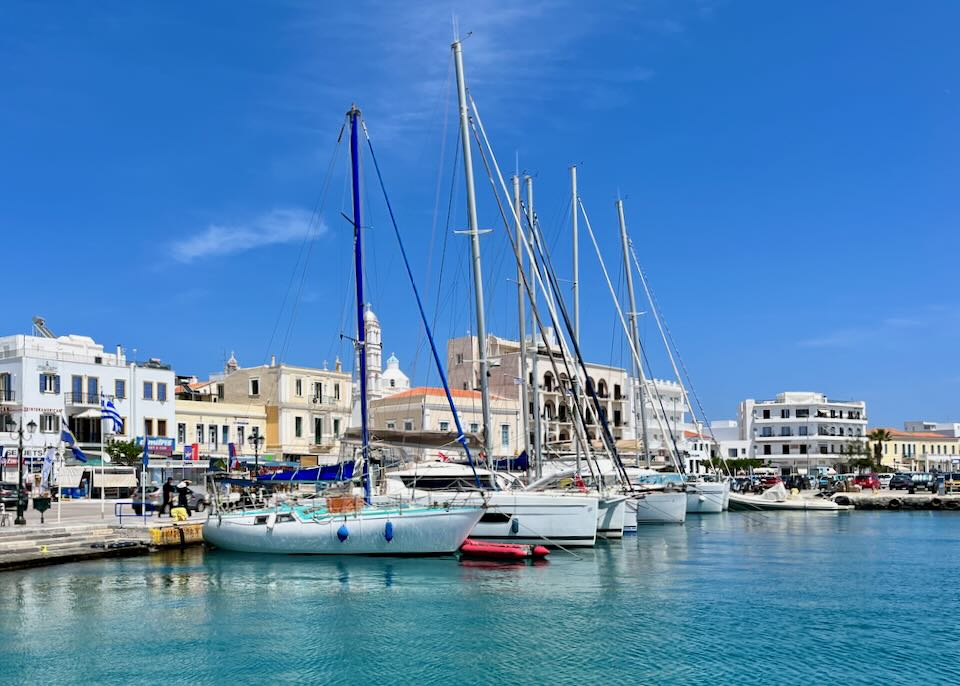 View of a Greek village as seen from its waterfront, lined with sailboats and yachts