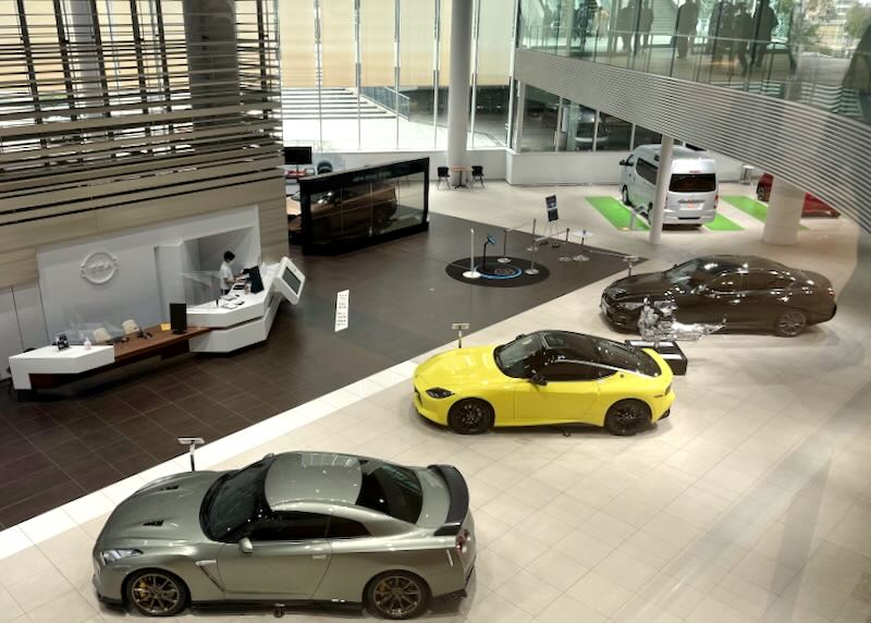Three sports cars, one yellow, sit in the Nissan Global Headquarters.
