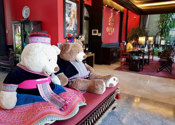 Two stuffed teddy bears sit in the lobby of a hotel.