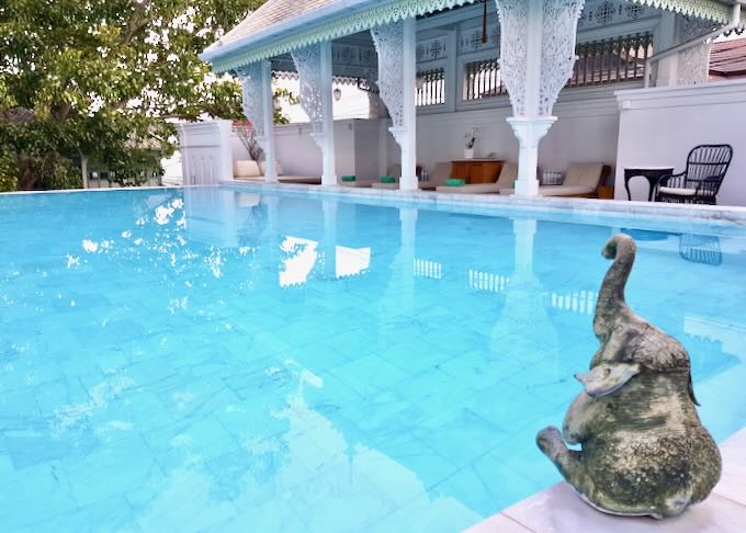 A pool with a small statue of an elephant.