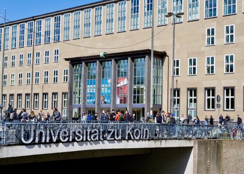 students in front of the main entrance of cologne university