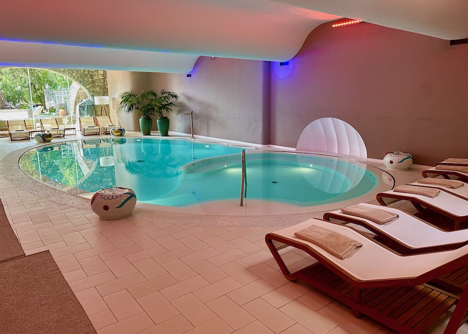 Oval-shaped indoor pool with lounge chairs on both ends at Hotel Piccolo Sant'Andrea in Praiano on the Amalfi Coast