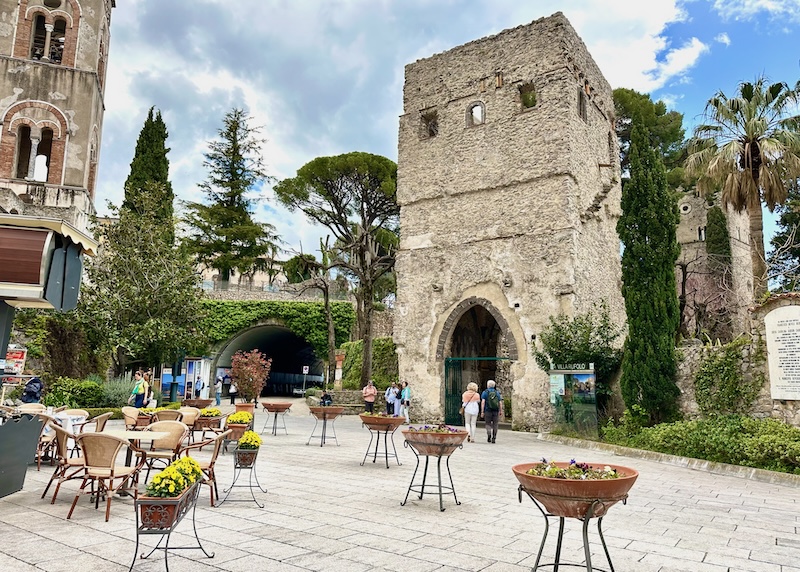 Piazza with a stone tower, bell tower, and planters with yellow flowers in Ravello on the Amalfi Coast