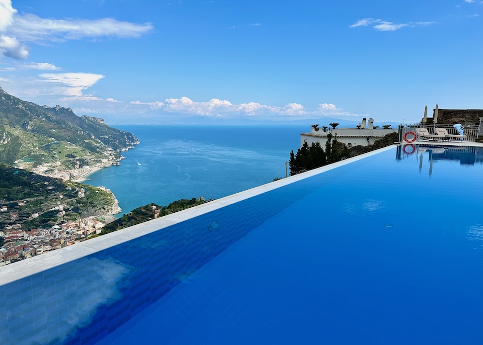 An infinity pool on a mountain with views down to the sea and two villages at Caruso hotel in Ravello on the Amalfi Coast