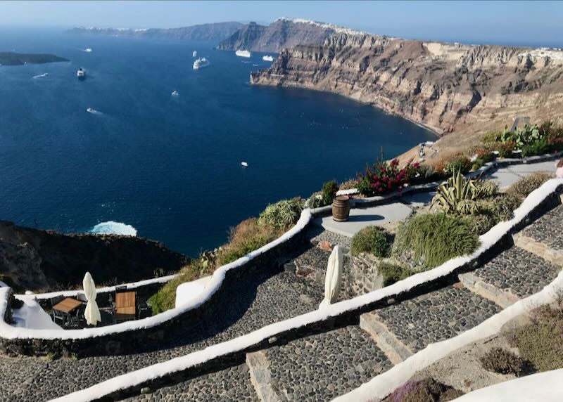Stone stairs leading down to a tasting patio on a caldera cliff overlooking the sea