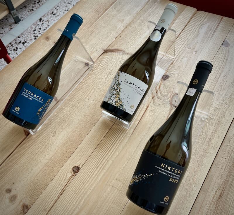 Three wine bottles, displayed on a wooden table.