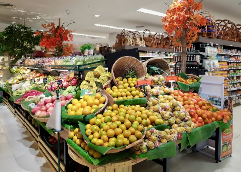 Piles of vibrant produce sits in baskets inside a supermarket.