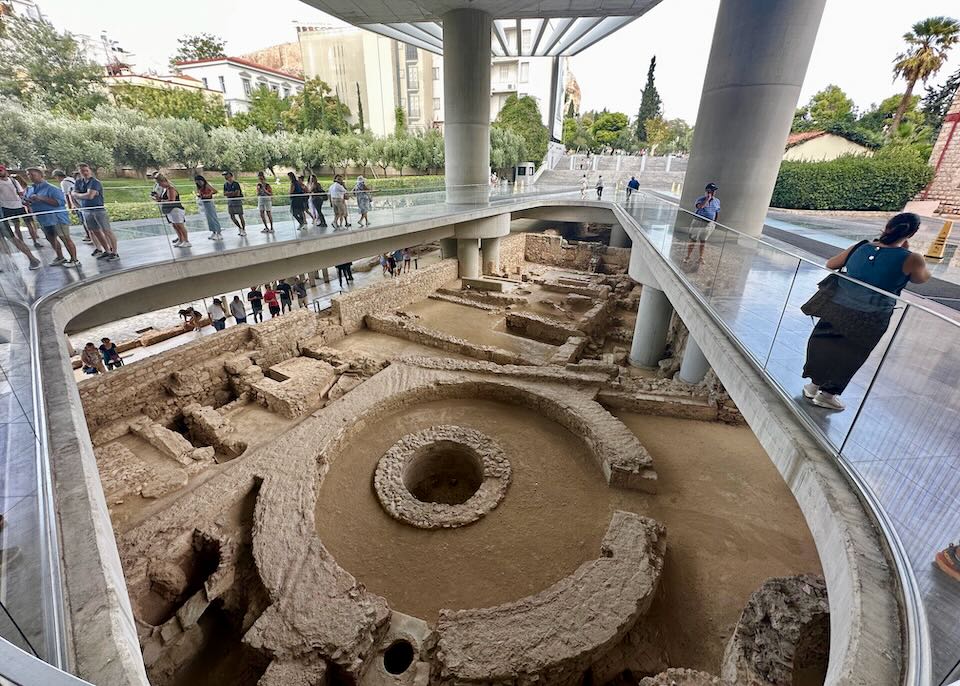 People look down from above over ancient excavated ruins.