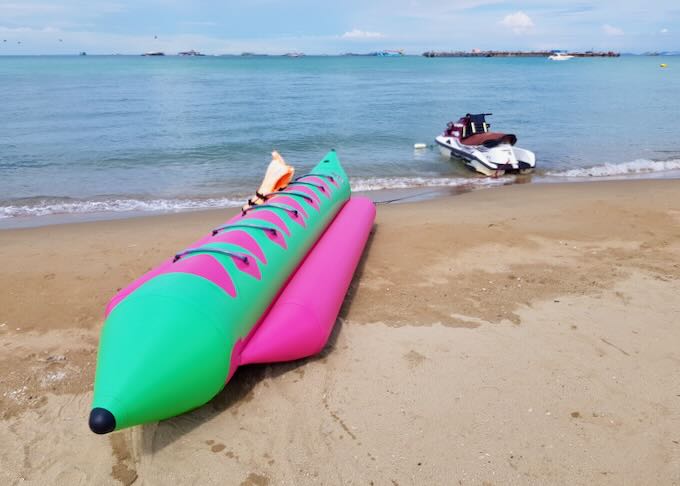 A bright green and pink inflatable boat sits on the beach.