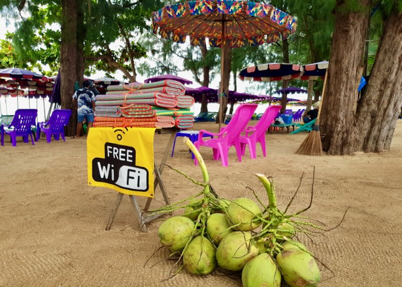 A green branch of coconuts lay on the freshly raked beach next to folded colorful mats and chairs.