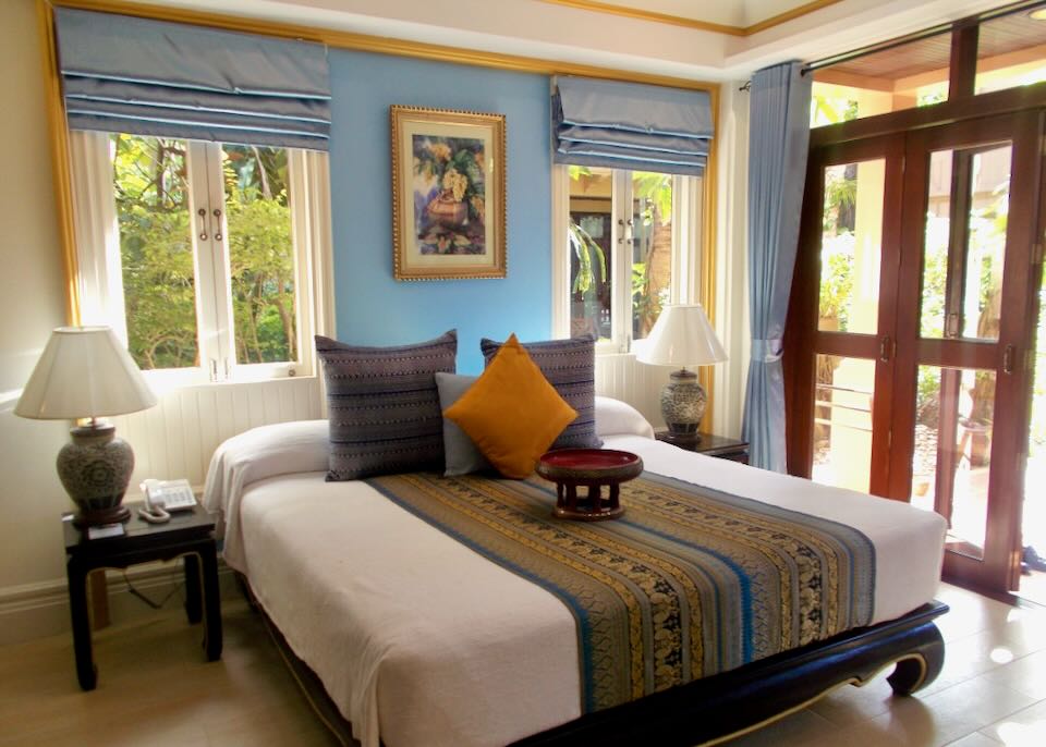 A large bed is dressed with a hand woven blanket and pillows.