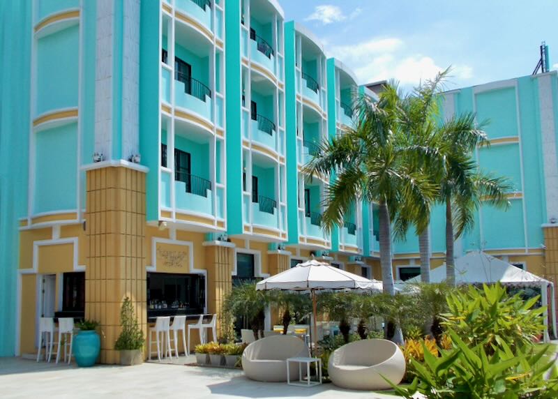 A bright teal and yellow hotel with palm trees.