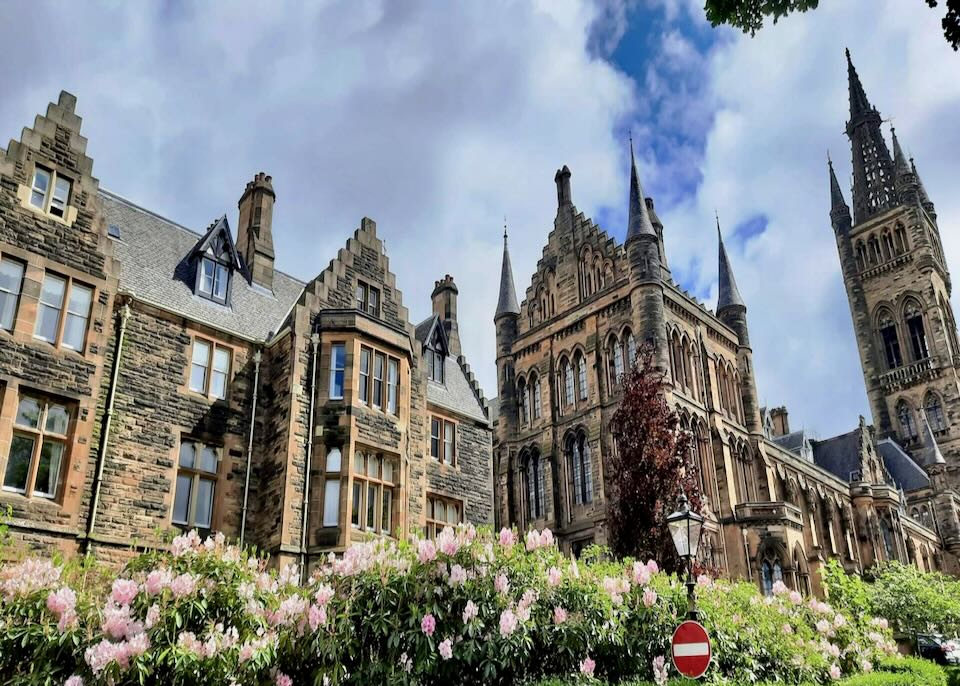 Main building of University of Glasgow, viewed over flowering bushes in spring