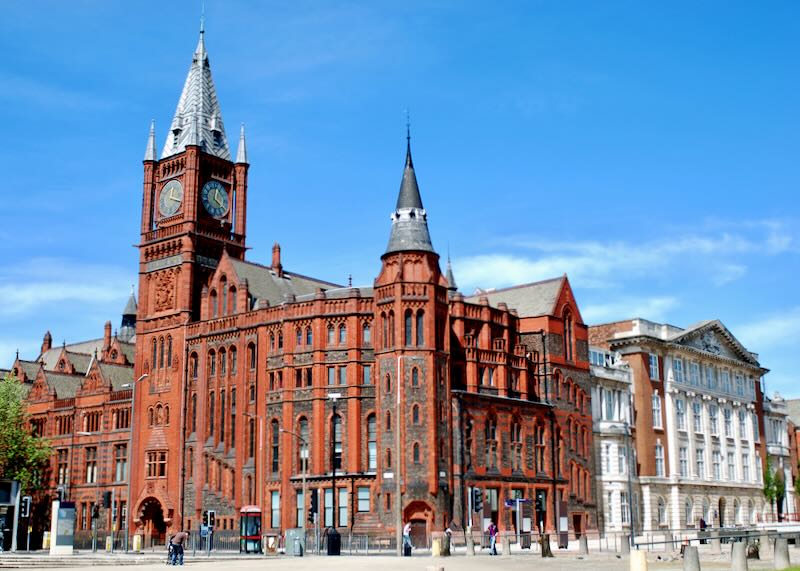 red brick building with copper spires rising against the blue sky.